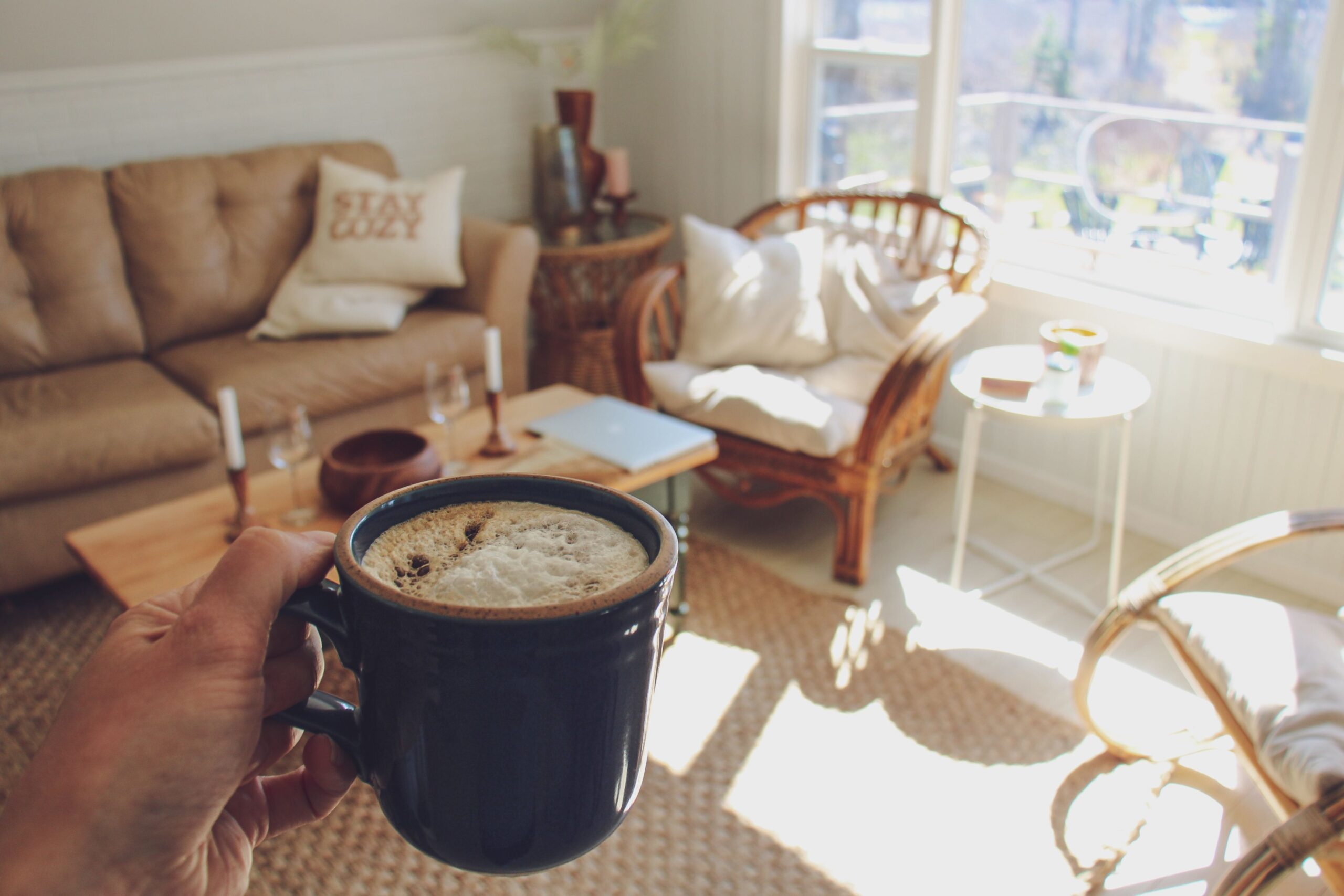 Enjoy a peaceful moment with coffee in a bright, cozy living room with warm sunlight.